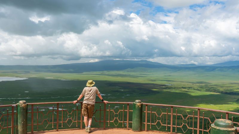 Panoramic view from viewing site of Ngorongoro Crater in wet season with tourist on viewing platform, Tanzania