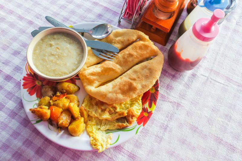 Tradition Nepal breakfast set, soup, omelette, bread, potato fried on pink-checked cloth