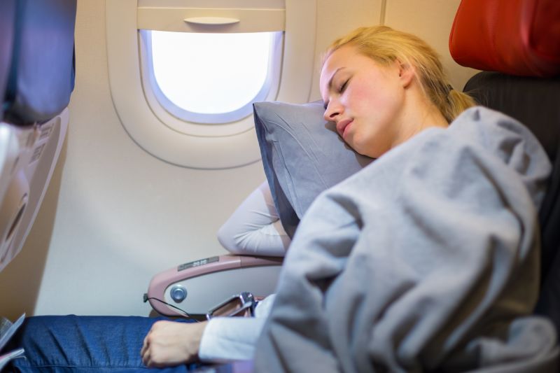 Ours. Young blonde woman sleeping on a plane by the window