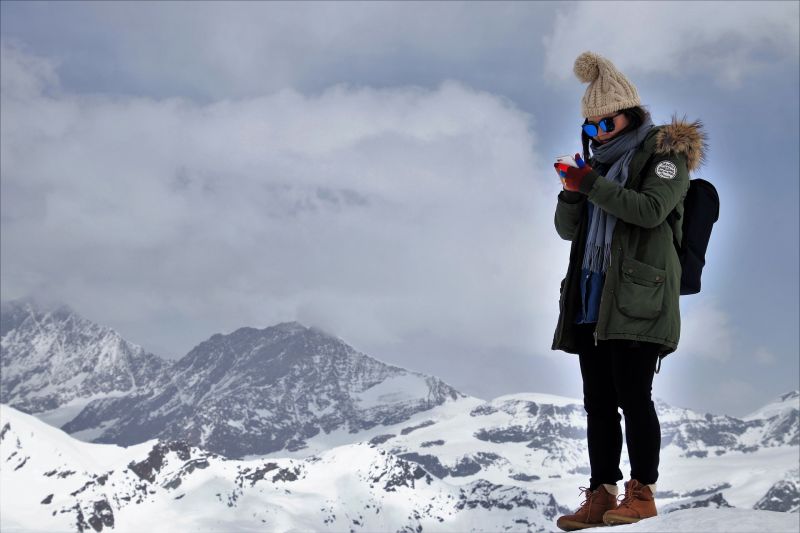 Warmly dressed woman with smartphone in the snowy Alps