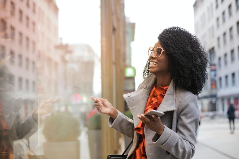 Black woman in coat looking at shop window on a city street