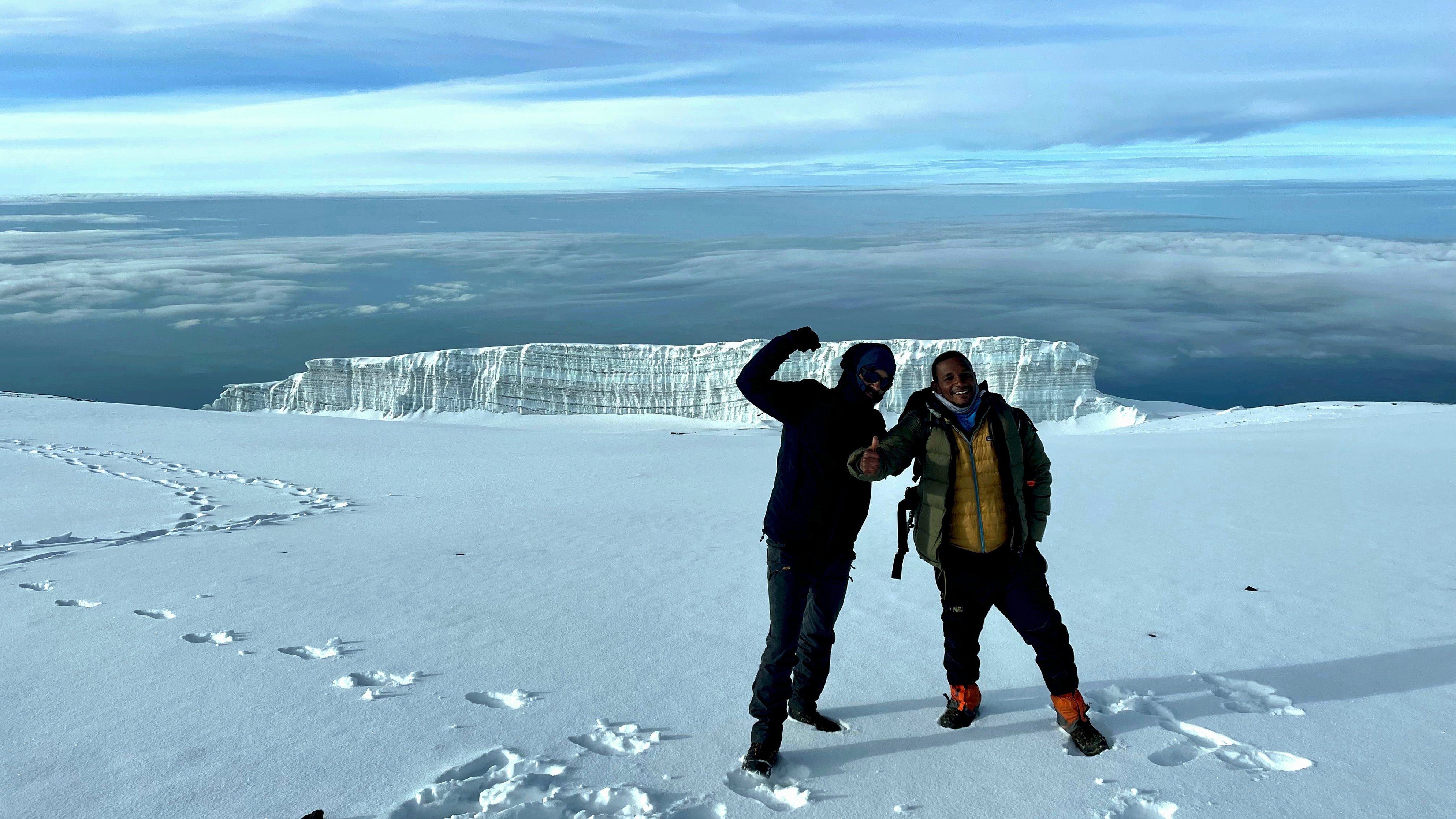 Two trekkers in the snow near the summit of Kilimanjaro with glacier behind them