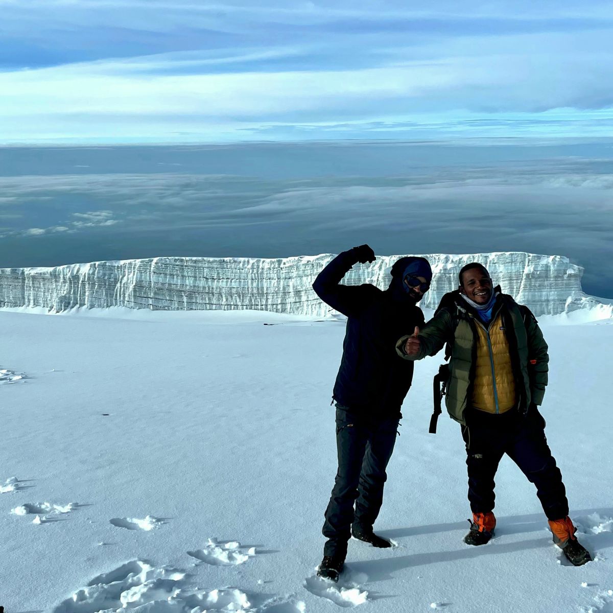 Two trekkers in the snow near the summit of Kilimanjaro with glacier behind them