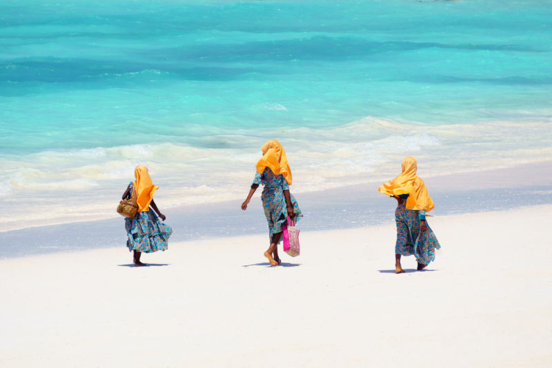 Zanzabari Muslim girls walking along the sandy beach in Zanzibar
