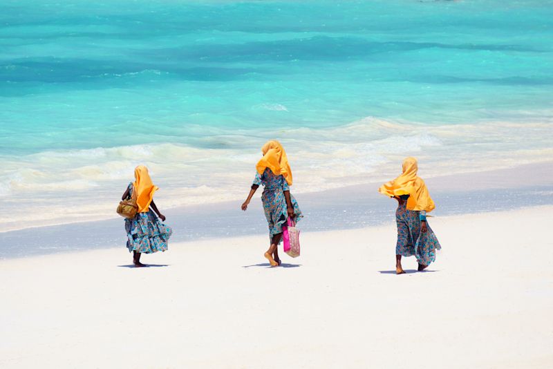 Zanzabari Muslim girls walking along the sandy beach in Zanzibar