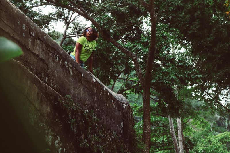 Woman peering down from high up in a forest setting