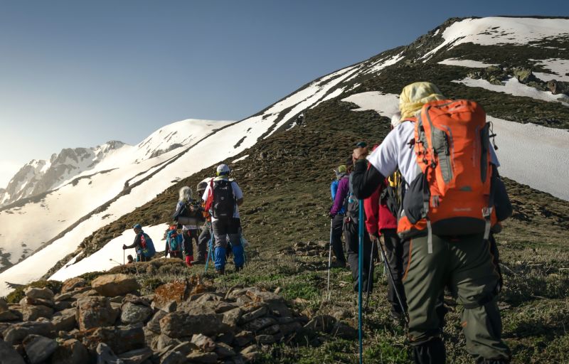 Hikers wearing backpacks and using trekking poles walking in snowy mountains