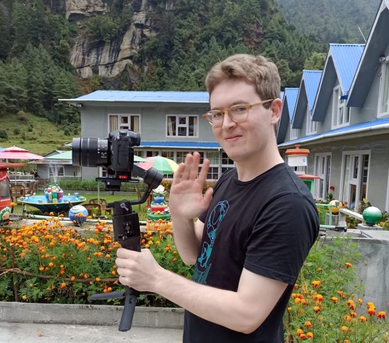 Man holding video camera and waving at camera on EBC trek, Nepal