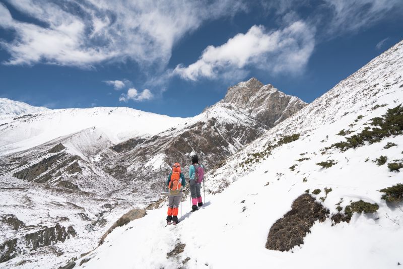 2 female trekkers hiking in snow towards Thorung La on Annapurna Circuit, Snowy landscape in Annapurna circuit,trekking in Nepal