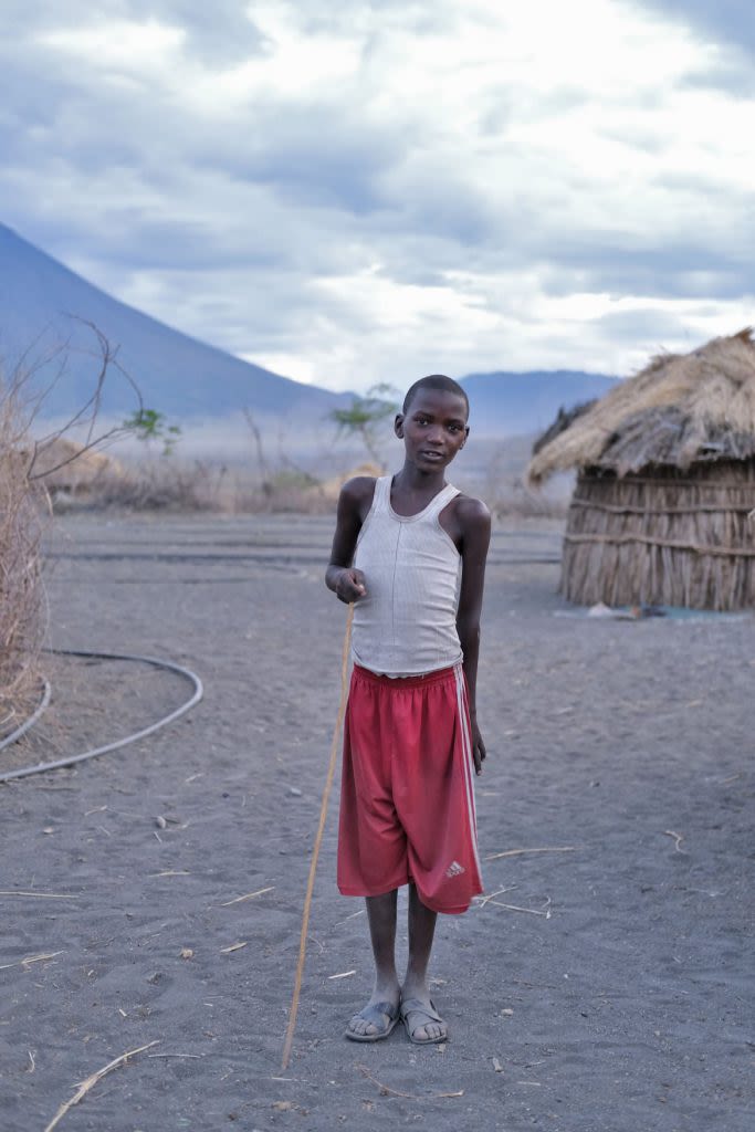 Maasai boy in red shorts and hollding a stick