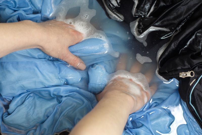 Woman handwashing a blue and black sleeping bag
