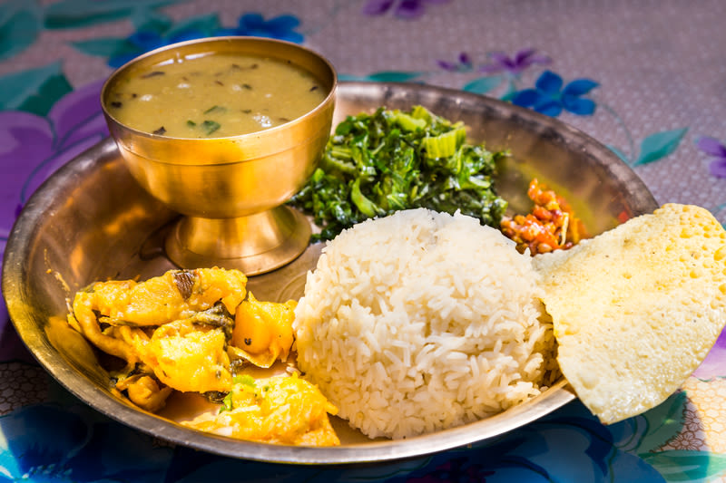 Ours. Nepali dal bhat with poppadam served in metal plate and sitting on a floral naplkin