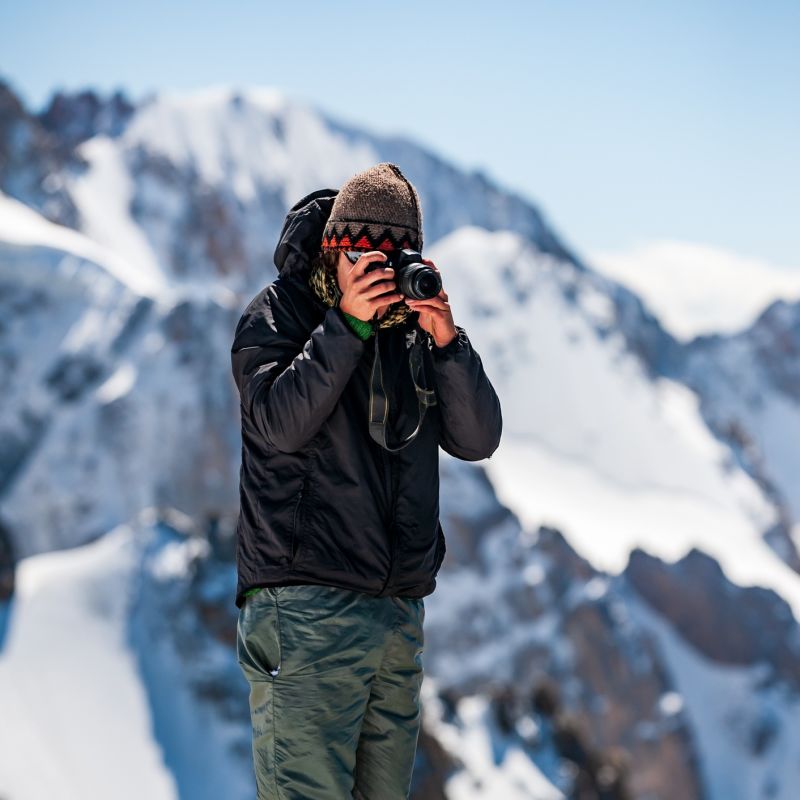 Man holding camera while standing in snowy mountain landscape