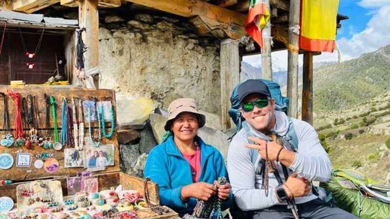 Smiling trekker with Nepali woman selling handmade jewellery on Annapurna Circuit