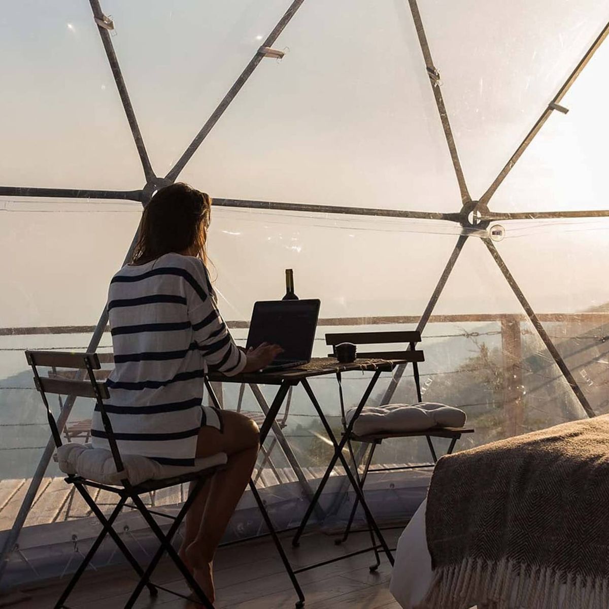 Woman sitting at desk in hotel room with views of hills