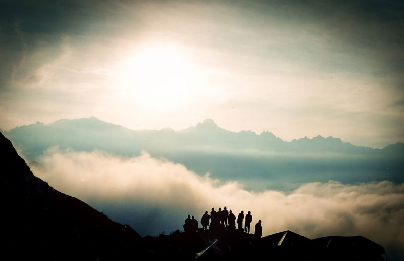 Silhouette of group of Inca Trail trekkers standing with Andes mountains behind them and clouds below