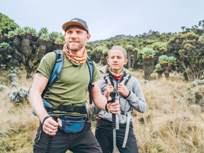 Blonde father and son (child) with trekking poles on Umbwe route of Kilimanjaro, moorland zone