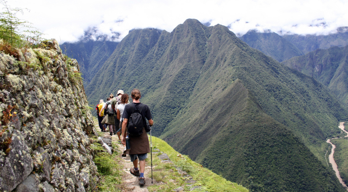 Trekkers on contour path of Inca Trail with river far below, Peru