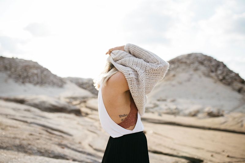 Girl with tattoo putting on jersey in desert