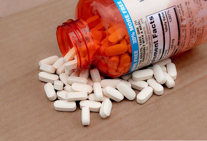 Vitamins or supplements spilling out of bottle on table