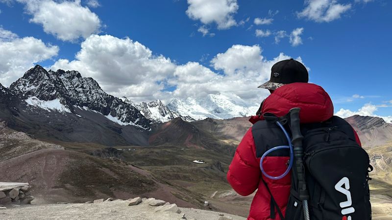 Man looking from Rainbow Mountain to other snow-capped peaks, Peru