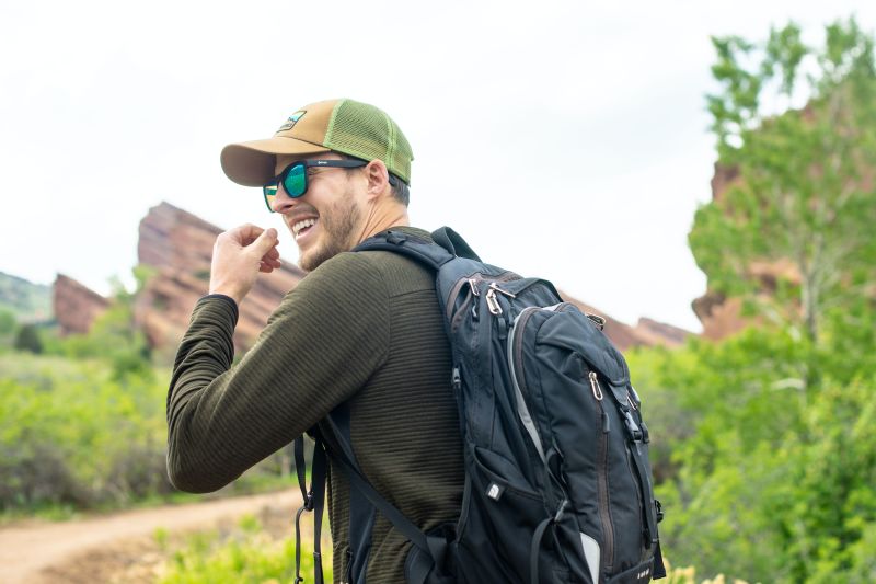 Smiling male hiker wearing cap, sunglasses and backpack