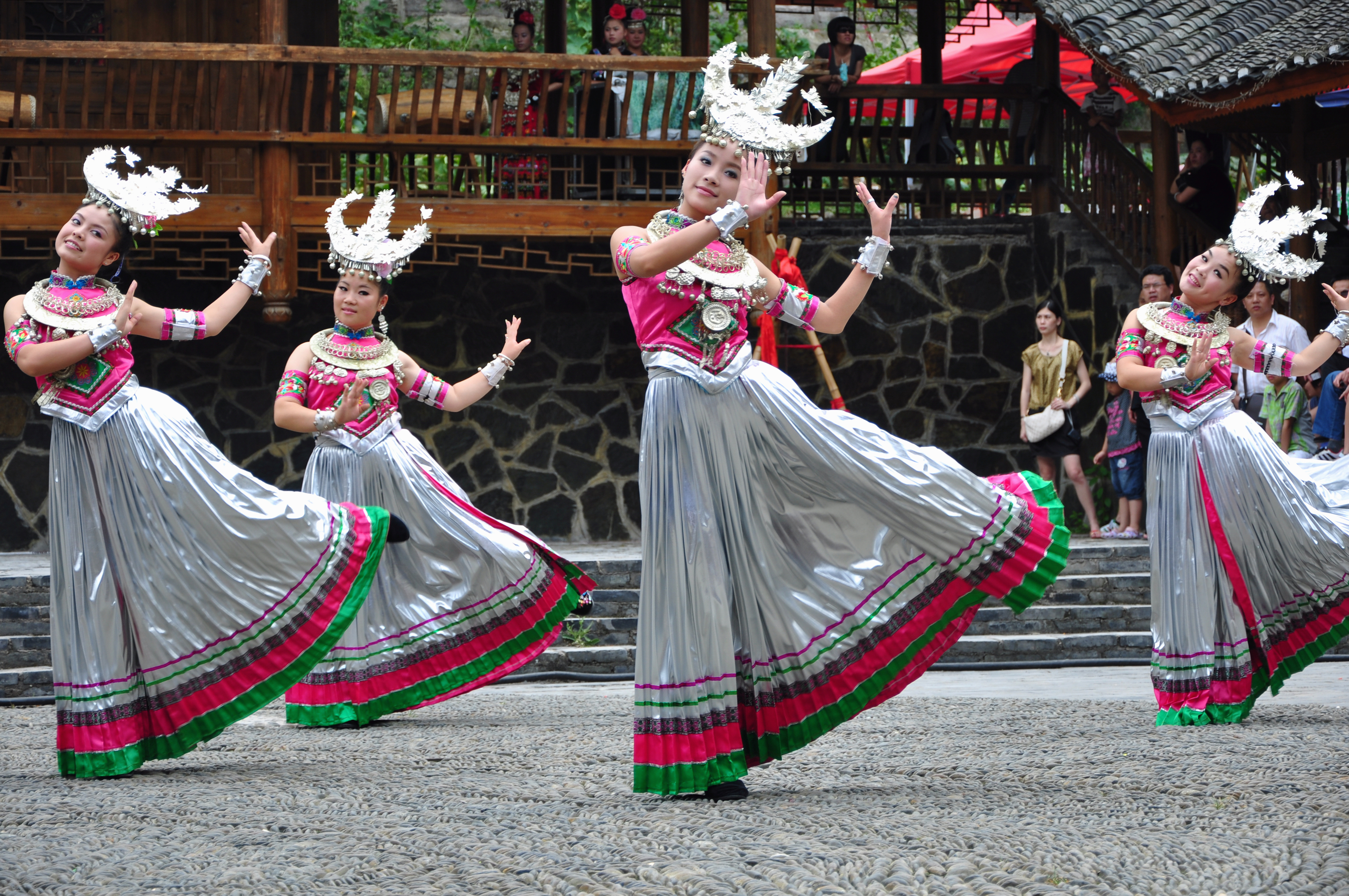 A group of Chinese women dressed in traditional folk costumes standing on the shore of the Tuojiang River in Fenghuang Old Town, Hunan Province.