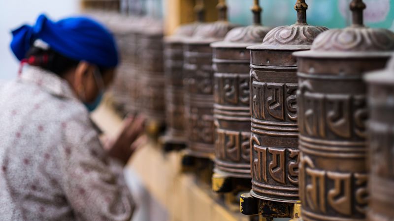Prayer wheels and woman who pray at Boudhanath Stupa in Kathmandu, Nepal