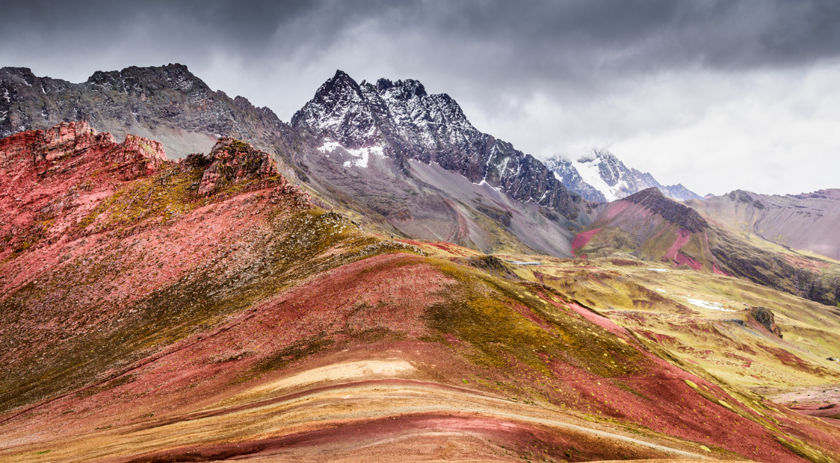 Beautiful ochre colour on Rainbow mountain with dusting of snow on the peaks in the background, Peru
