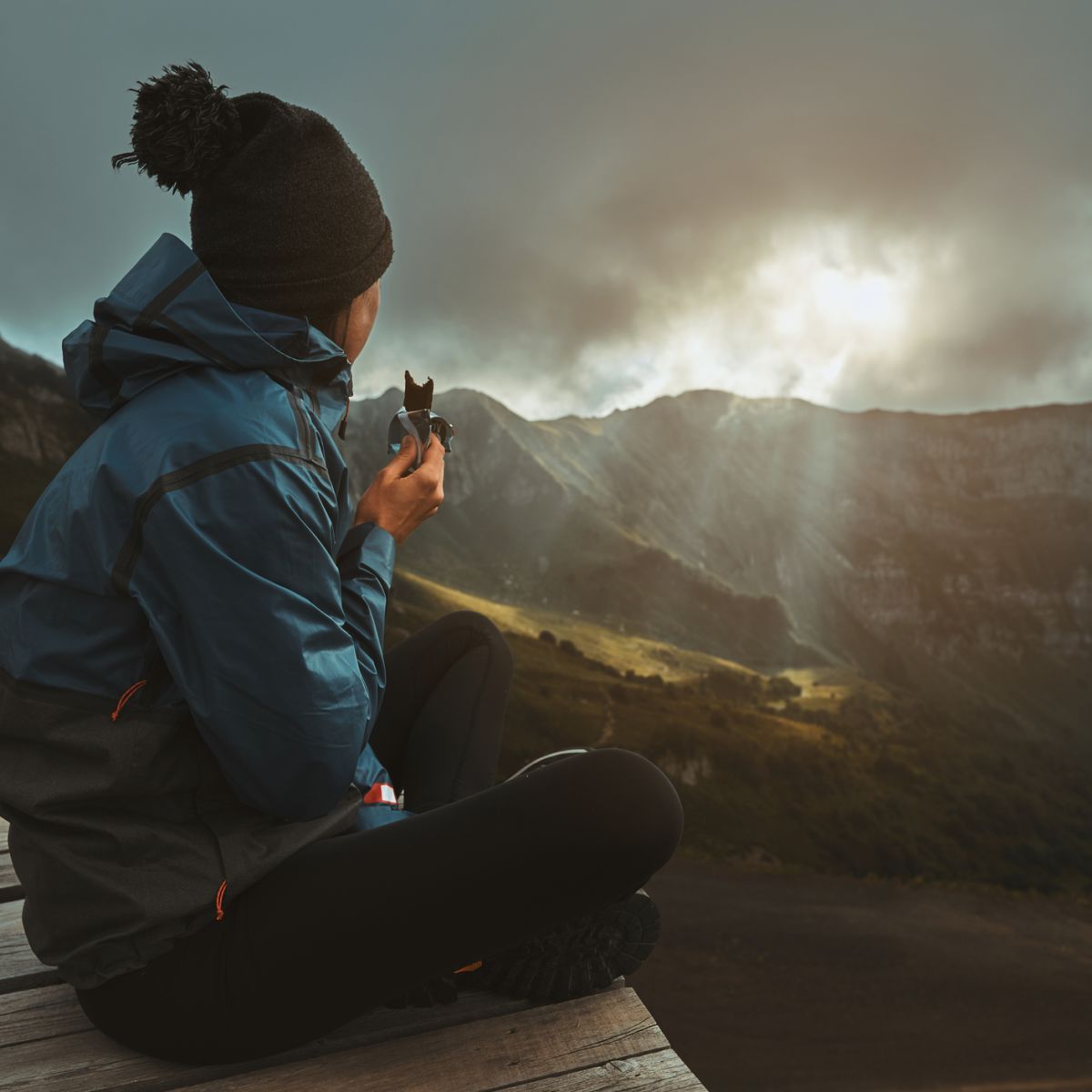 Female hiker seated on boardwalk with moody sky in cold climate