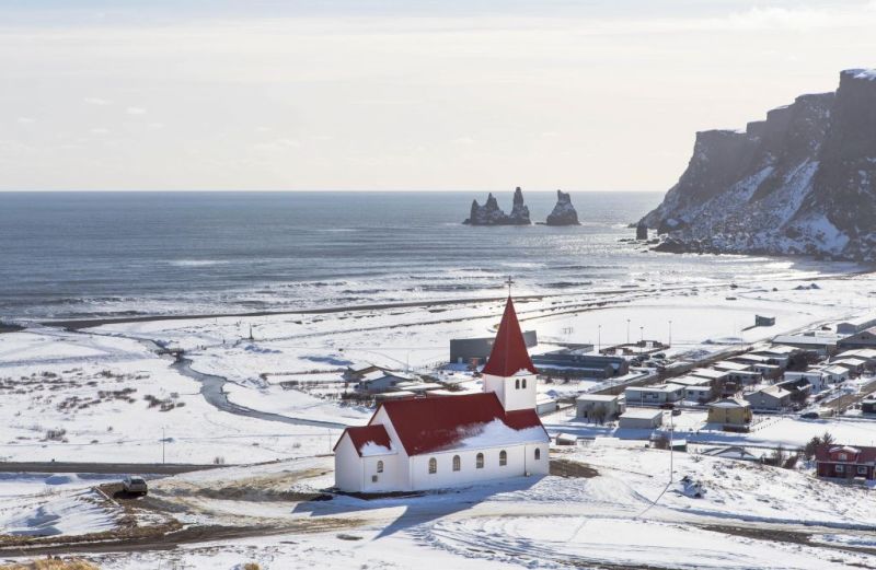 View from above of Vík village by sea covered in snow