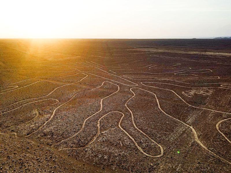 Aerial view of the Nazca Lines at sunset, depicting ancient geoglyphs in the Peruvian desert landscape.