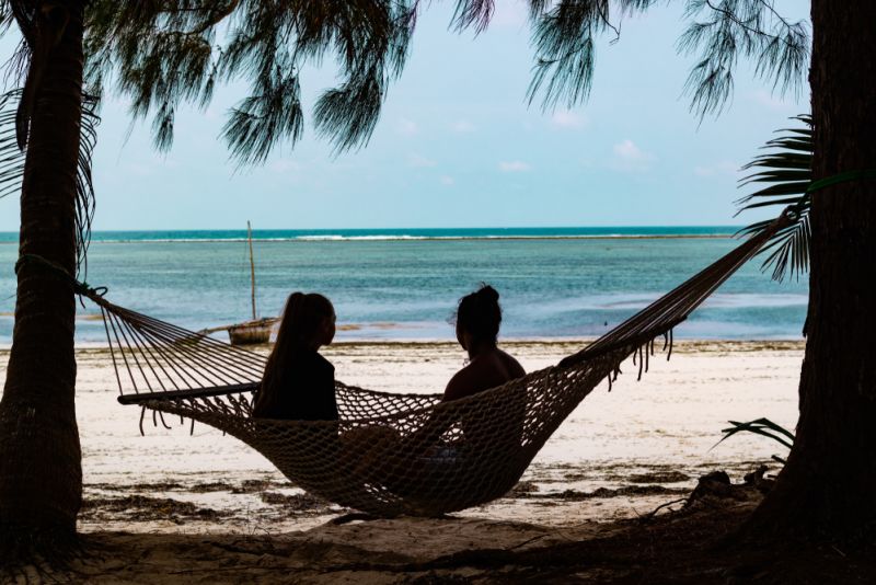 Two girls seated in a hammock overlooking the ocean in Zanzibar
