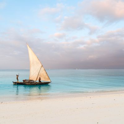 Beautiful sunrise over ocean with fishing boat, fishermen, Nungwi, Kendwa, Zanzibar island, Tanzania