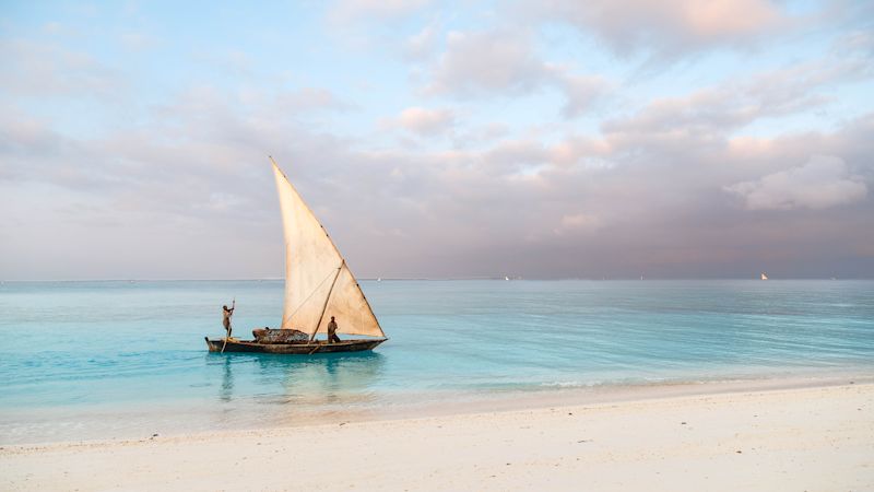 Beautiful sunrise over ocean with fishing boat, fishermen, Nungwi, Kendwa, Zanzibar island, Tanzania