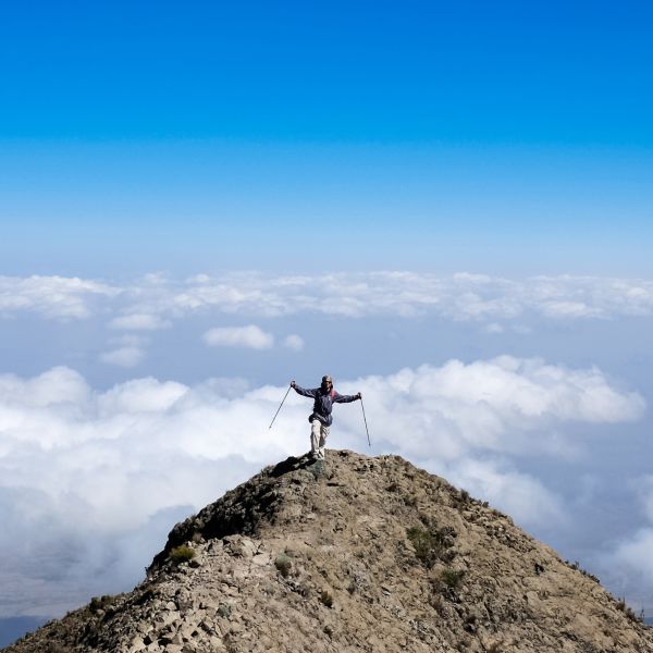 Trekker on Socialist Peak on Mt Meru with clouds behind 