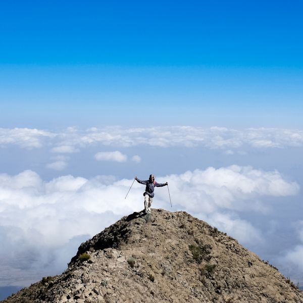 Trekker on Socialist Peak on Mt Meru with clouds behind 