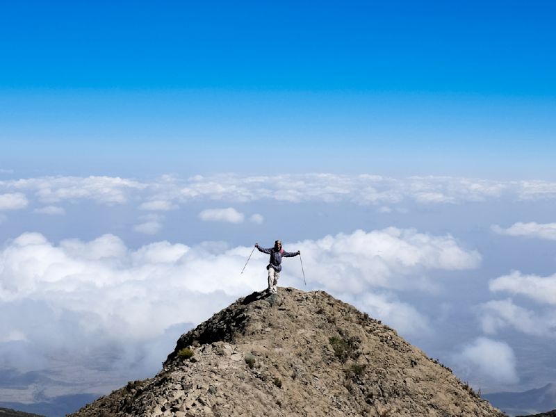 Trekker on Socialist Peak on Mt Meru with clouds behind 