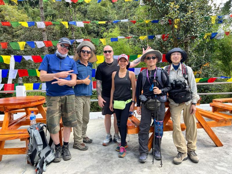 Group of smiling trekkers on the EBC trek with prayer flags in background, Nepal