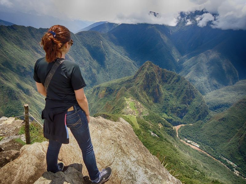 Redheaded woman looking down at Machu Picchu in Peruvian Andes