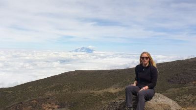 Tash sitting on a rock on Kilimanjaro with cloud bank below