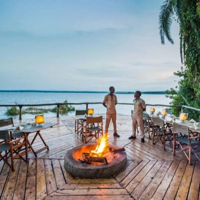 Fire and staff on verandah by lake at Ruzizi Tented Lodge in eastern Rwanda