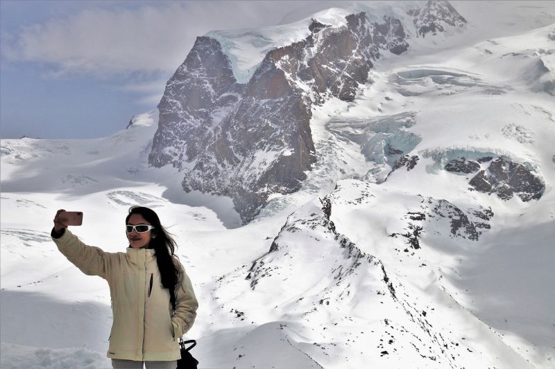 Woman taking selfie while standing in snowy mountainous landscape