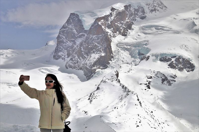 Woman taking selfie while standing in snowy mountainous landscape