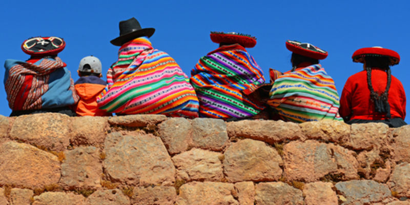 Quechua ladies and a young boy chatting on an ancient Inca wall