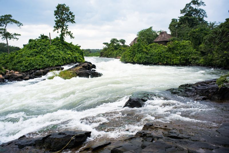 Rushing Nile River flowing past thatched roof in Jinja, Uganda