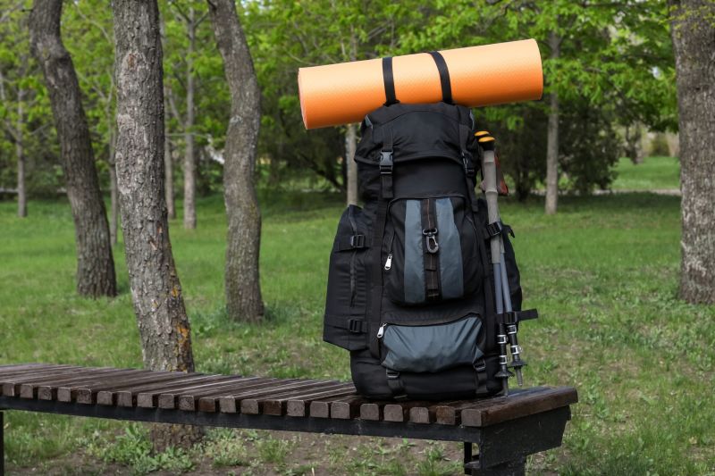 Black-and-grey backpack with sleeping roll sitting on an outside bench