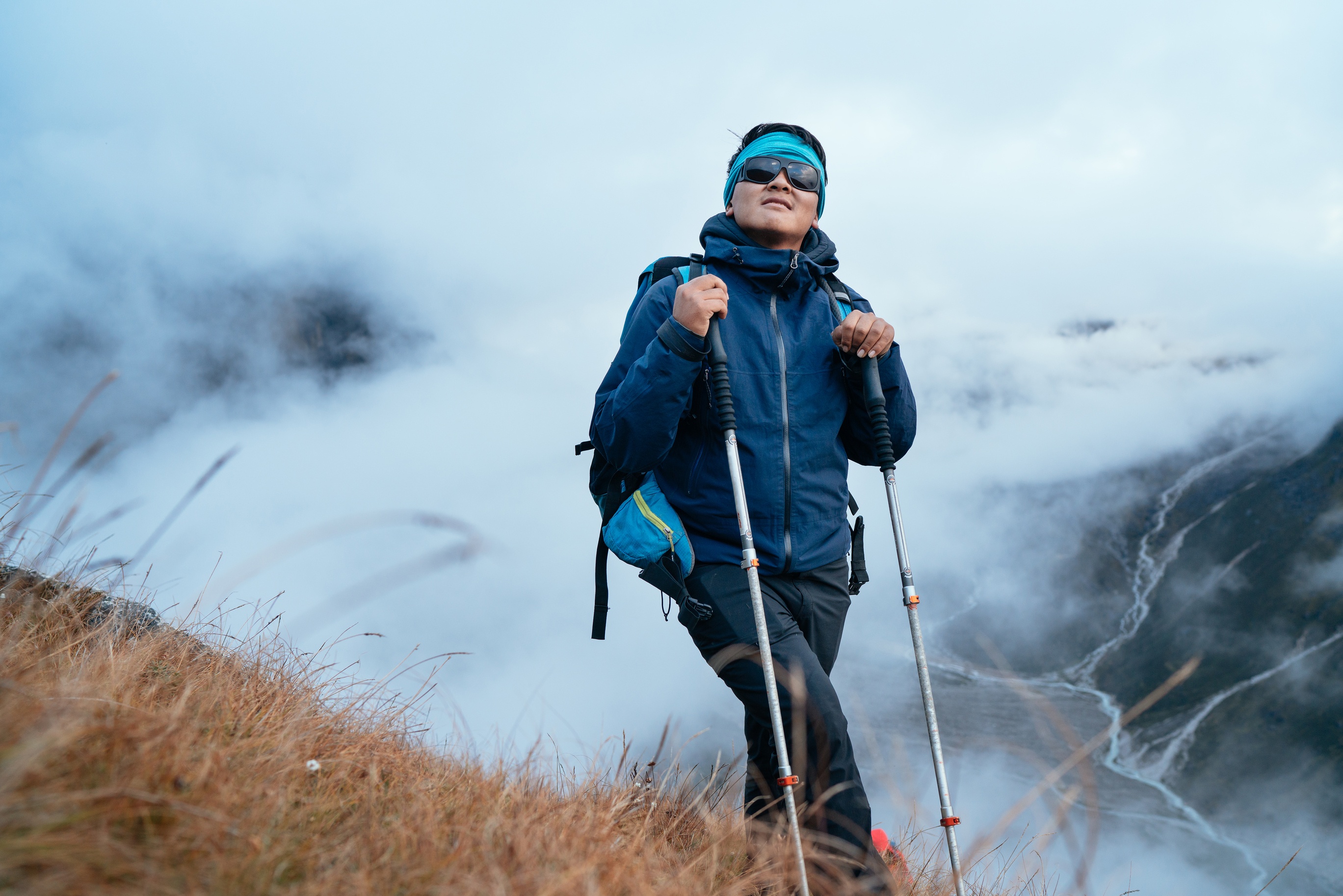 Smiling Sherpa men in sunglasses backpacker with trekking poles hiking and enjoying Mera peak climbing acclimatization walk on Makalu Barun Park route.