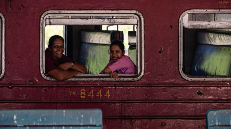 Mother and daughter smiling while looking out the train window in Kandy, Sri Lanka