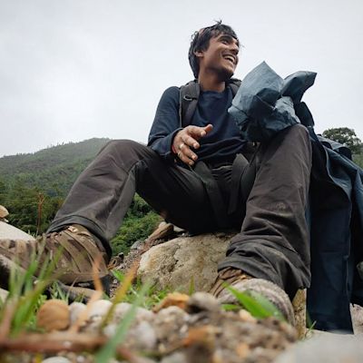 Man in hiking gear sitting on a rock outdoors, low angle